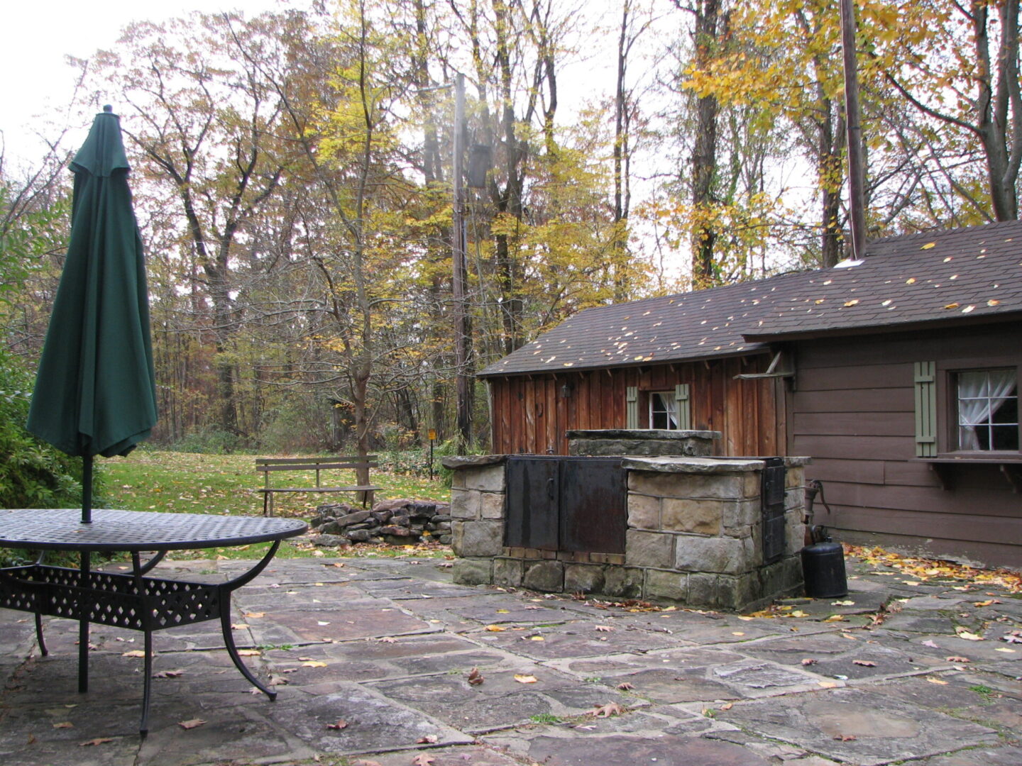 Stone patio with a cabin and umbrella.