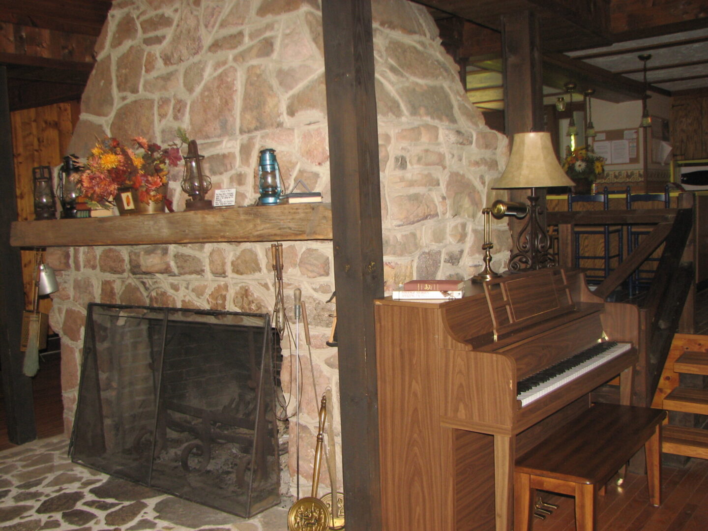 Stone fireplace with piano and lamp.