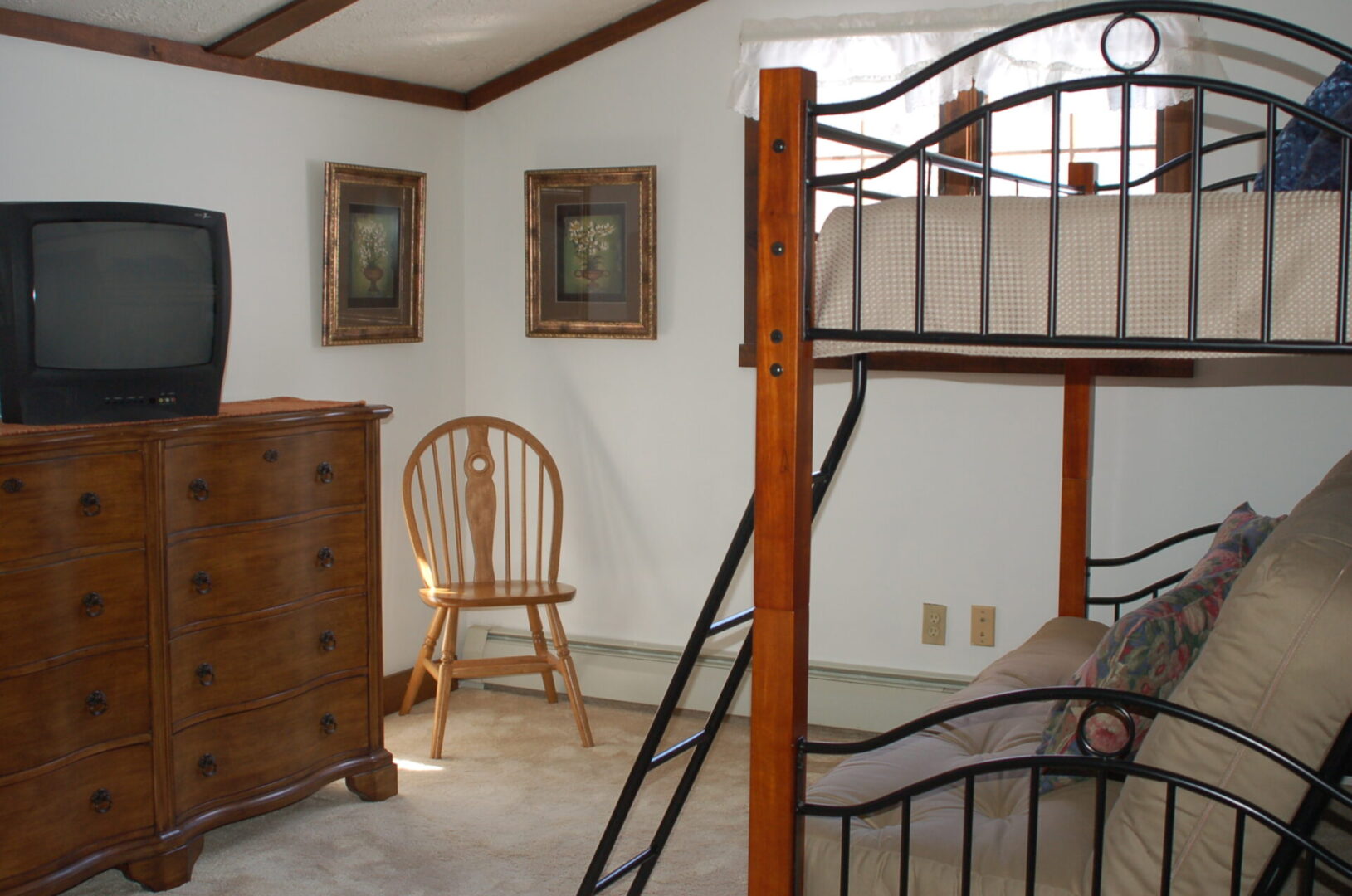 A bedroom with a bunk bed, dresser, and TV.