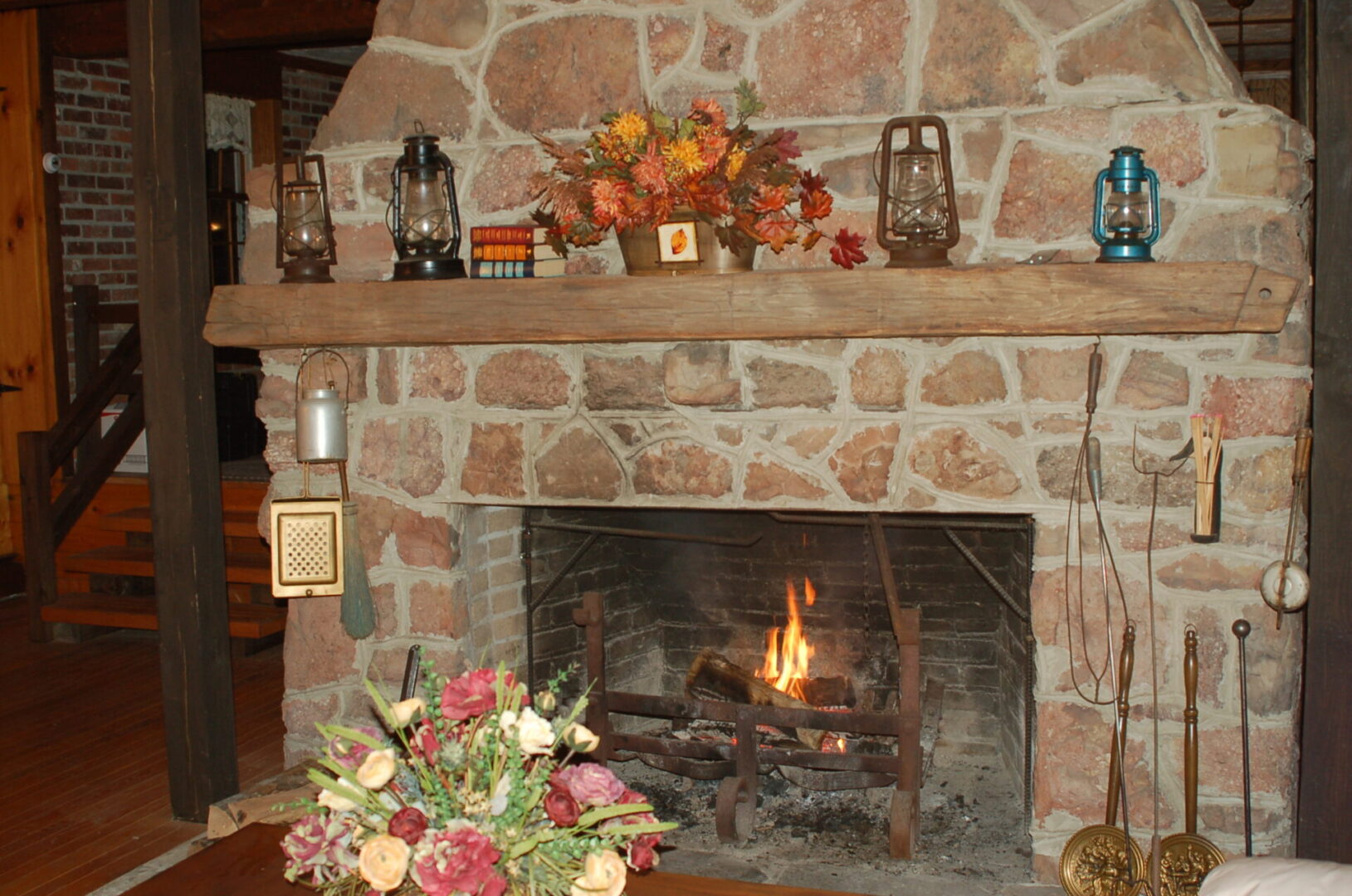 Stone fireplace with burning fire and lanterns.