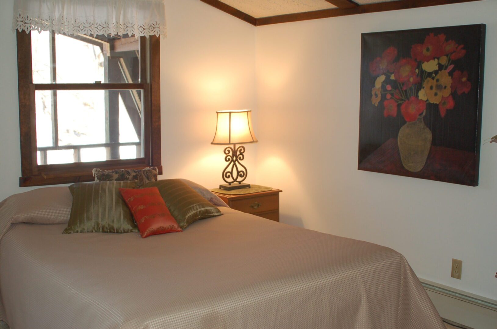 Bedroom with bed, lamp, and floral painting.